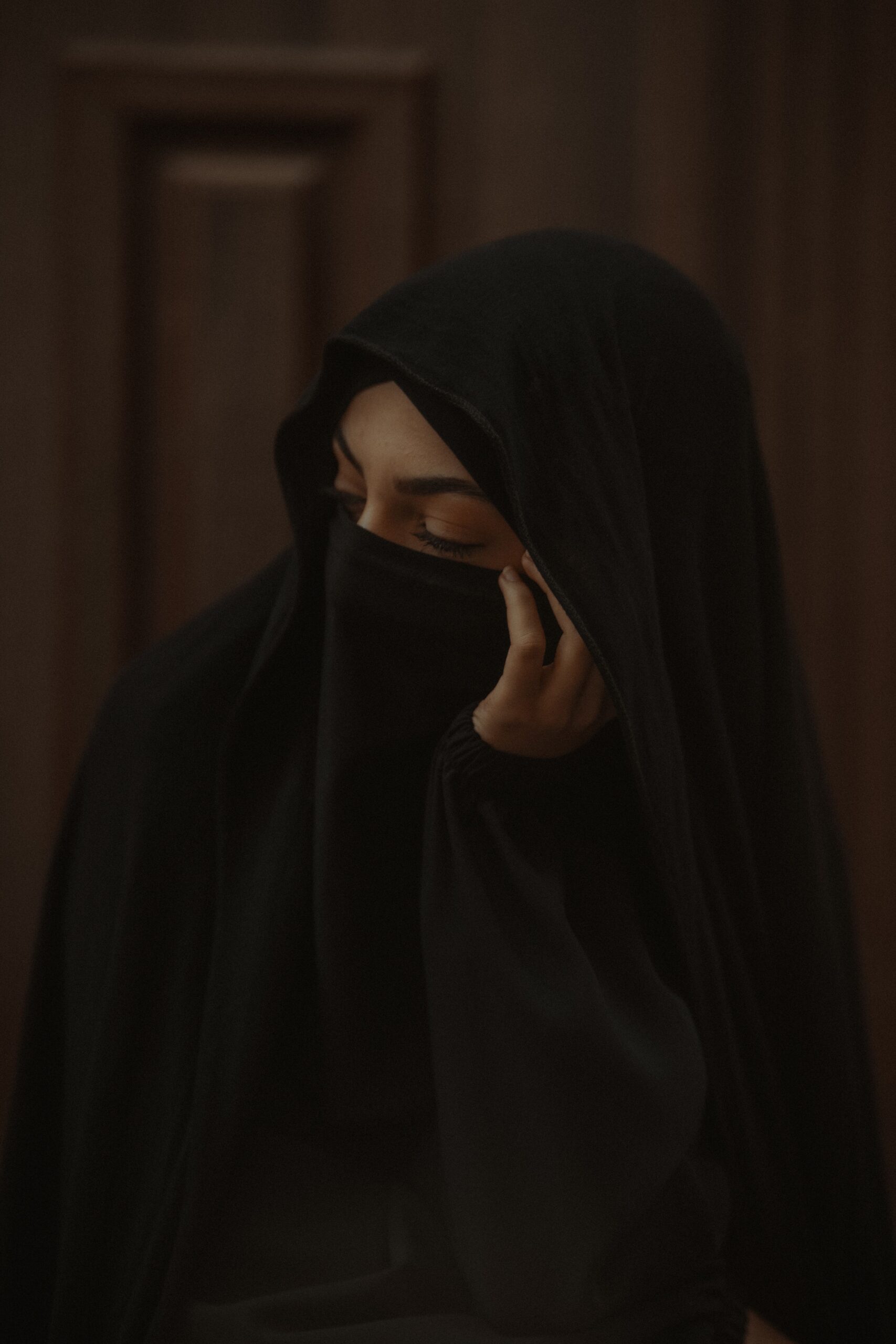 A contemplative woman in hijab and veil, eyes closed in a serene pose.
